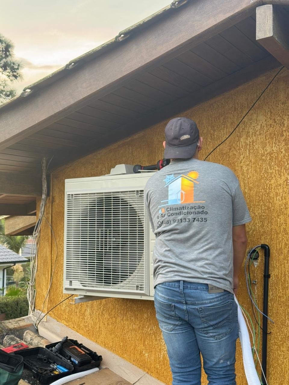 Técnico AS Climatização instalando condensadora Daikin R32 em área externa
